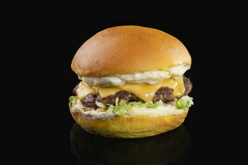 Cheeseburger met dubbele kaas en sla op een zwarte achtergrond